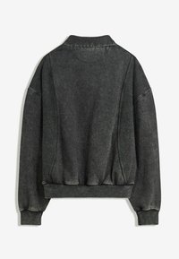 Pullover grigio scuro a maniche lunghe con polsini e orlo a coste, dotato di dettagli di cucitura visibili e una trama leggermente sbiadita su uno sfondo bianco.