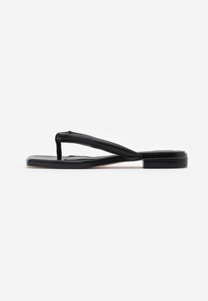 Sort flad sandal med tyk polstret tåsøm og firkantet tå, vist fra siden på hvid baggrund.