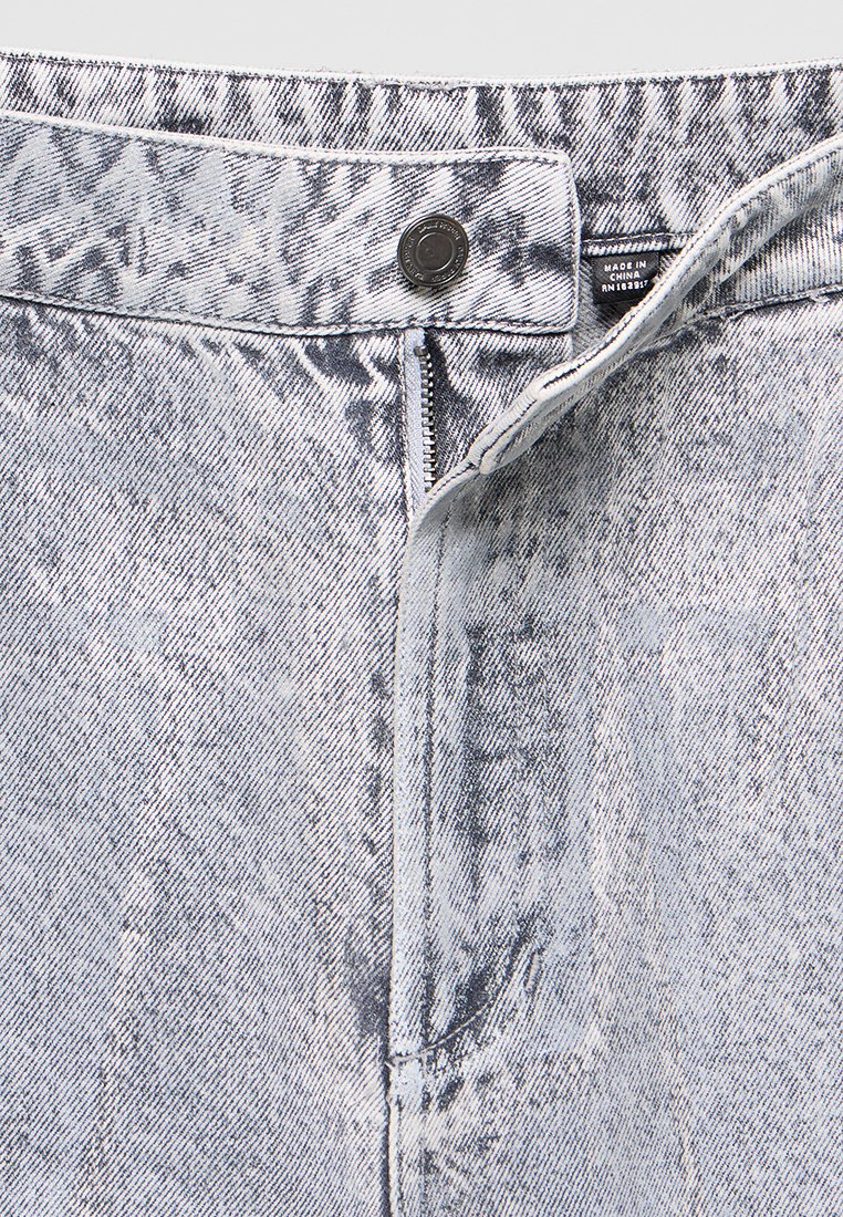 Licht gewassen denim jeans met gedeeltelijk geopend ritssluiting, metalen knoopsluiting en zichtbaar "Made in China" etiket aan de binnenkant van de tailleband.