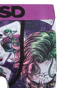 Páska na spodním prádle v purpurové barvě s černými písmeny "SD", obsahující podrobné ilustrace postavy Jokera a hracích karet na látce.