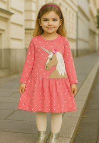 Rosa Polka-Dot-Kleid mit Einhorn-Grafik und Blumenakzent, langen Ärmeln, gerafftem Rock, kombiniert mit weißen Strumpfhosen und silbernen Stiefeln.