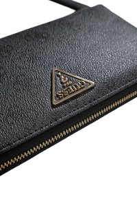 Pochette in pelle nera con texture, dotata di una cerniera dorata e un badge logo triangolare sul davanti. Design compatto e dettagli hardware minimali.