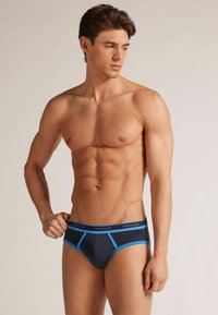 Männer-Dunkelgraue Slips mit hellblauen Akzenten, die über einen unterstützenden Beutel und einen elastischen Bund mit dem Markenzeichen verfügen. Glattes Baumwollmaterial.