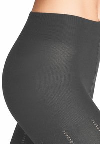 Hoch taillierte schwarze Leggings mit einer gerippten Textur und gemusterten Akzenten, die eine glatte Oberfläche und eine enge Passform an der Taille bieten.