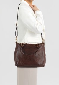 Bruine leren handtas met een gestructureerde afwerking, metalen accenten langs de bovenrand en een enkele verstelbare schouderband.