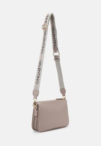Sac en cuir taupe clair à porter en bandoulière avec quincaillerie dorée. Il présente une large bandoulière avec le logo "VALENTINO", un dessus zippé et un panneau texturé subtil.