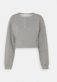 Felpa grigia cropped realizzata in un tessuto morbido, con scollatura arrotondata, patta con tre bottoni e maniche lunghe con polsini a coste.