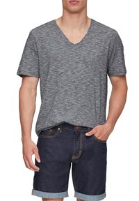 Szary melanż, krótki rękaw, koszulka typu V-neck w połączeniu z granatowymi szortami dżinsowymi, z podwiniętymi manszetami i widocznymi detalami szwów.