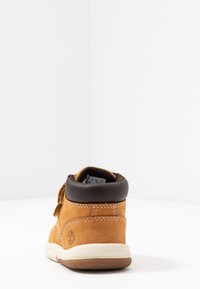 Brown leather ankle boot with a padded collar, white sole, and contrasting stitching. Features a logo on the outer side.