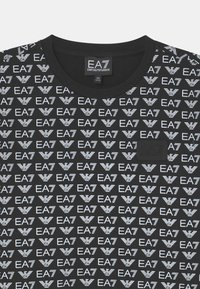 Black cotton t-shirt featuring a repeated white EA7 logo pattern, round neckline, and a textured black label with embossed logo.