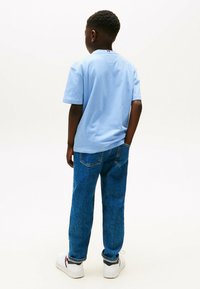 Lichtblauw, kortemouwt-shirt, van katoen, met contrasterende kraagdetails, gecombineerd met relaxte blauwe jeans en witte sneakers.
