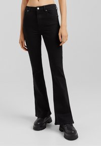 Mustat leveälahkeiset farkut, jotka on valmistettu denimistä, sisältävät puolivälin vyötärön, viisi taskua, hopeiset yksityiskohdat ja pienehkön joustavuuden mukavuutta varten.