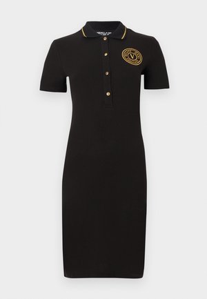 Must lühikeste varrukatega polomehekleit kuldsete nööpidega, kuldse logoga rinnal ja kuldse äärisega krae ümber.