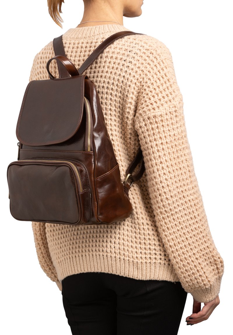 Bruine leren rugzak met klepsluiting, ritsen en meerdere vakken. Glad en textuur oppervlak, verstelbare leren banden.