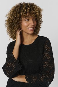 Black lace top featuring three-quarter length sleeves with scalloped edges. Fabric has a textured floral pattern. Smooth neckline.