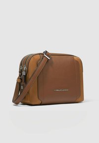 Braune Leder-Umhängetasche mit silbernen Beschlägen, Reißverschluss und verstellbarem Riemen. Verfügt über eine glatte Textur und ein modernes Design.