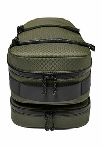 Grüne Tasche mit zwei Fächern und diamantförmigem Muster, mit schwarzen Reißverschlüssen und Akzenten. Hergestellt aus recycelten Materialien, glatte Textur.