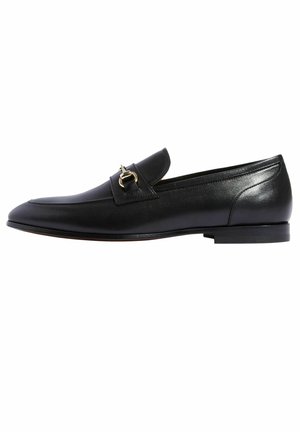 Schwarze Lederloafers mit abgerundetem Zehenbereich, einem goldenen Schnallenakzent und einem niedrigen, gestapelten Absatz. Glatte Oberfläche mit minimalen Nähten.