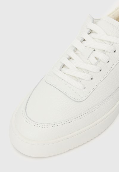 Λευκά δερμάτινα sneakers με υφασμάτινη επιφάνεια, επίπεδους κορδόνες και καουτσούκ σόλα. Διαθέτει διακριτές ραφές και μινιμαλιστικό σχεδιασμό.