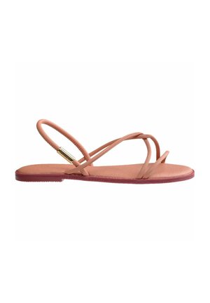 Sandali piatti con sottili cinturini rosa chiaro e una soletta testurizzata. Presentano una suola bordeaux e un accento metallico sui cinturini.
