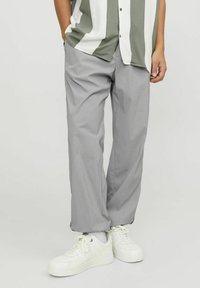 Lys grå bukser med løs pasform, lavet af glat stof. Parret med hvide sneakers, der har en subtil glans og elastisk talje.