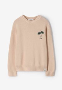 Pull en maille beige avec poignets et ourlet côtelés, arborant une petite broderie de palmier vert sur le côté gauche de la poitrine.