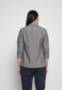 Grå kavaj med texturerad finish, skräddarsydd passform och slag. Har uppvikta ärmar och en medellång rygg.