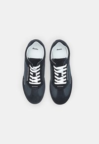 Scarpe sportive nere con tomaia in camoscio, pannelli laterali in rete e lacci bianchi. Marchio ben visibile sulla linguetta e sul lato.