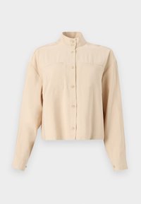 Beige, cropped button-up shirt with a high collar, two chest pockets, long sleeves, smooth texture, and round buttons.