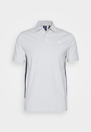 Camisa polo blanca con diseño de cuello, tapeta de botones, mangas cortas y paneles laterales en azul marino. Fabricada en algodón.