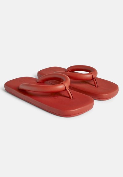 Røde gummiflip-flops med flad sål og runde mellemrumsstropper. Overfladen er glat og har et enkelt design uden yderligere mønstre.