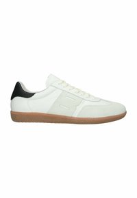 Baskets basses blanches avec semelle beige, patch noir au talon, lacets à l'avant et détail cousu sur le côté sur fond blanc uni.