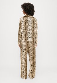 Set din satin cu imprimeu de leopard format din două piese, compus dintr-o cămașă cu mânecă lungă, cu croială lejeră, și pantaloni largi în tonuri de bej și negru.