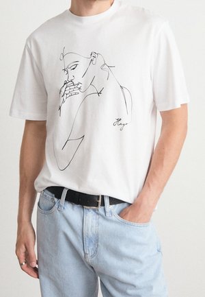 Wit katoenen T-shirt met een zwarte lijntekening van een vrouw en de merknaam "Hugo" vlakbij de onderkant.