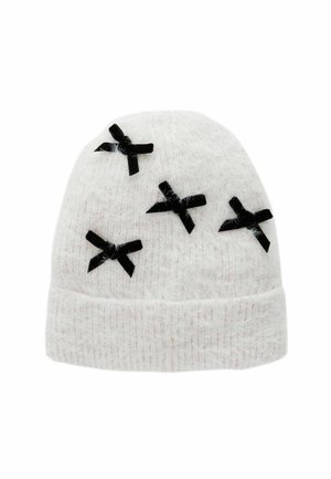 Bonnet en tricot blanc avec une texture douce, comportant cinq nœuds en tissu noir cousus sur la surface. Le design est rond et ajusté.