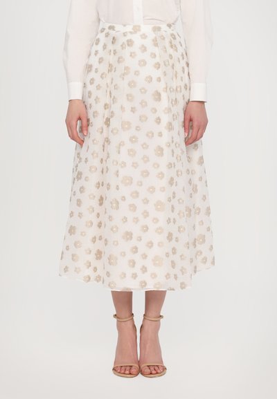 Witte rok met bloemenprint met beige geborduurde bloemen, A-lijn ontwerp en een gladde textuur. Gecombineerd met lichte, sandalen met bandjes.