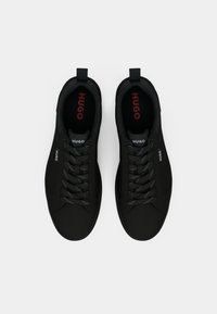 Sneakers neri con una texture liscia, punta rotonda e design con lacci. Branding rosso "HUGO" sulla linguetta e sui lati.