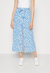 Lichtgewicht, blauw-wit patroon culottes met een gestrikte taille, voorzien van een losse pasvorm en wijde pijpen, gecombineerd met witte sneakers.