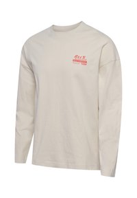 Bež majica z dolgimi rokavi z rdečim napisom "Bees Stadium Restaurant" in majhnim Hummel logotipom na levi strani prsnega koša.