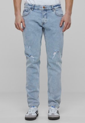 Light blue denim jeans with a relaxed fit, featuring distressed details and subtle fading. Styled with standard five-pocket design.