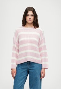 Pulôver malhado com riscas horizontais em rosa e branco, mangas largas, gola redonda e um corte descontraído. Combinado com jeans azuis.