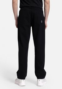 Black pants with a straight fit, featuring two back pockets and subtle logo detail. Made of fabric with a smooth texture and minimal design.