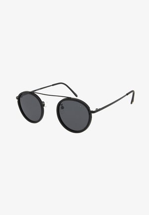 Gafas de sol redondas con montura de metal negra, lentes oscuros y brazos delgados. Almohadillas nasales ajustables para mayor comodidad. Diseño minimalista sin logotipos visibles.