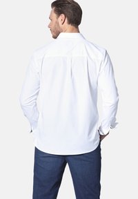 Weißes Langarmhemd mit klassischem Kragen, Knopfmanschetten und glatter Textur, kombiniert mit dunkelblauen Jeans.