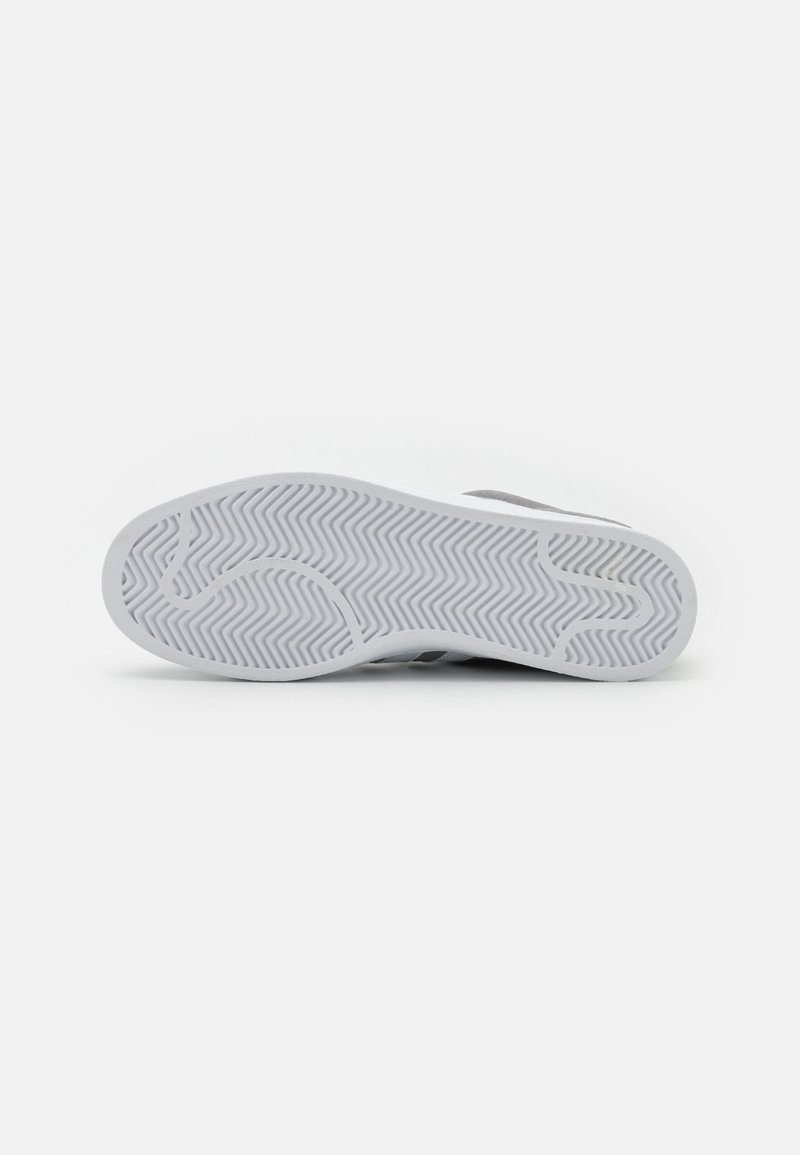 Grauer Sport-Schuhsohle mit einer strukturierten weißen Gummi-Oberfläche, die ein Fischgrätenmuster und einen Logo-Abdruck für besseren Halt aufweist.
