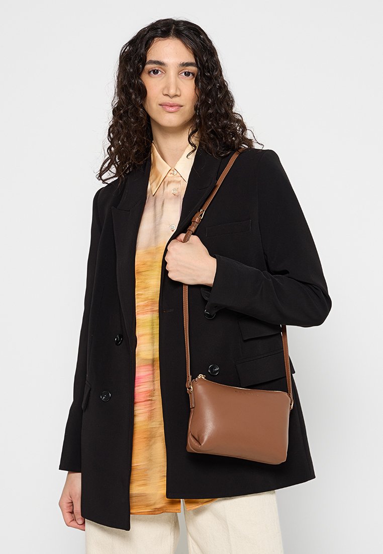 Borsa a tracolla in pelle marrone con una texture liscia, chiusura con zip e tracolla regolabile, presentata su uno sfondo neutro.