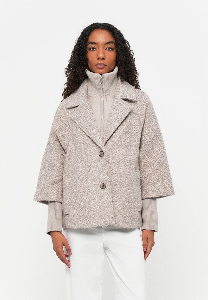 Veste en mélange de laine gris cendré avec des manches larges 3/4, un col à revers et deux boutons à l'avant. La couche intérieure possède une finition matelassée.