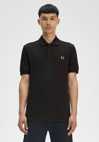 Camiseta polo negra con una abertura de dos botones, mangas cortas y un sutil logo bordado en el lado izquierdo del pecho. Fabricada en suave algodón.
