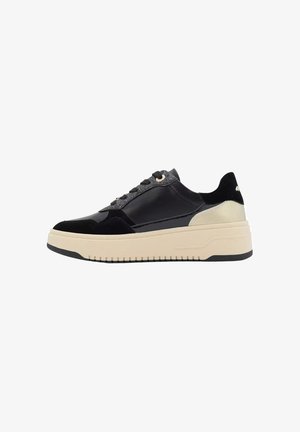 Sneakers neri con un mix di pelle verniciata e suede. Presentano una suola spessa di colore crema e dettagli metallici sul tallone e sugli occhielli.