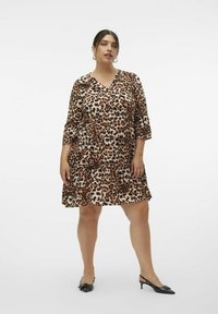 Leopardprikket kjole i brun og creme, med flared skørt, V-hals, trekvart ærmer, tekstureret stof, parret med sorte slingback hæle.